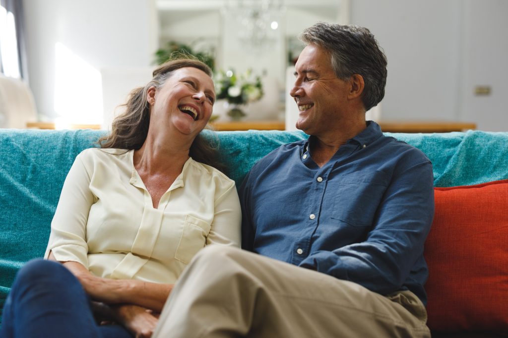 Happy senior caucasian couple in living room sitting on sofa, smiling
