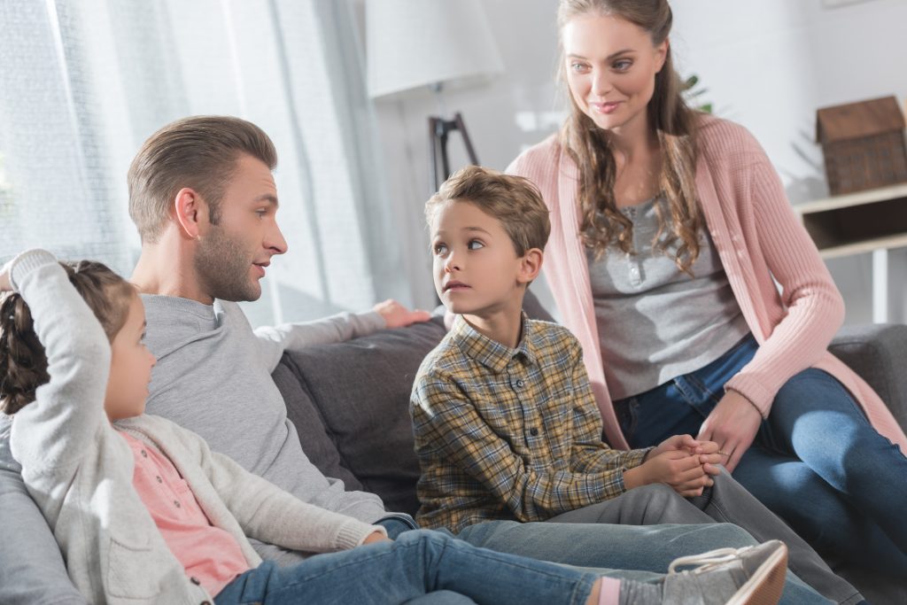 Dad sitting on couch with his kids and wife while telling them a story