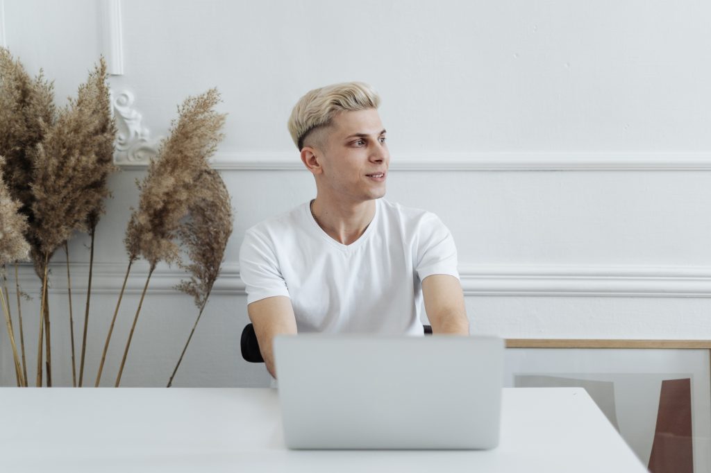 Man smiling working using computer laptop in a white space